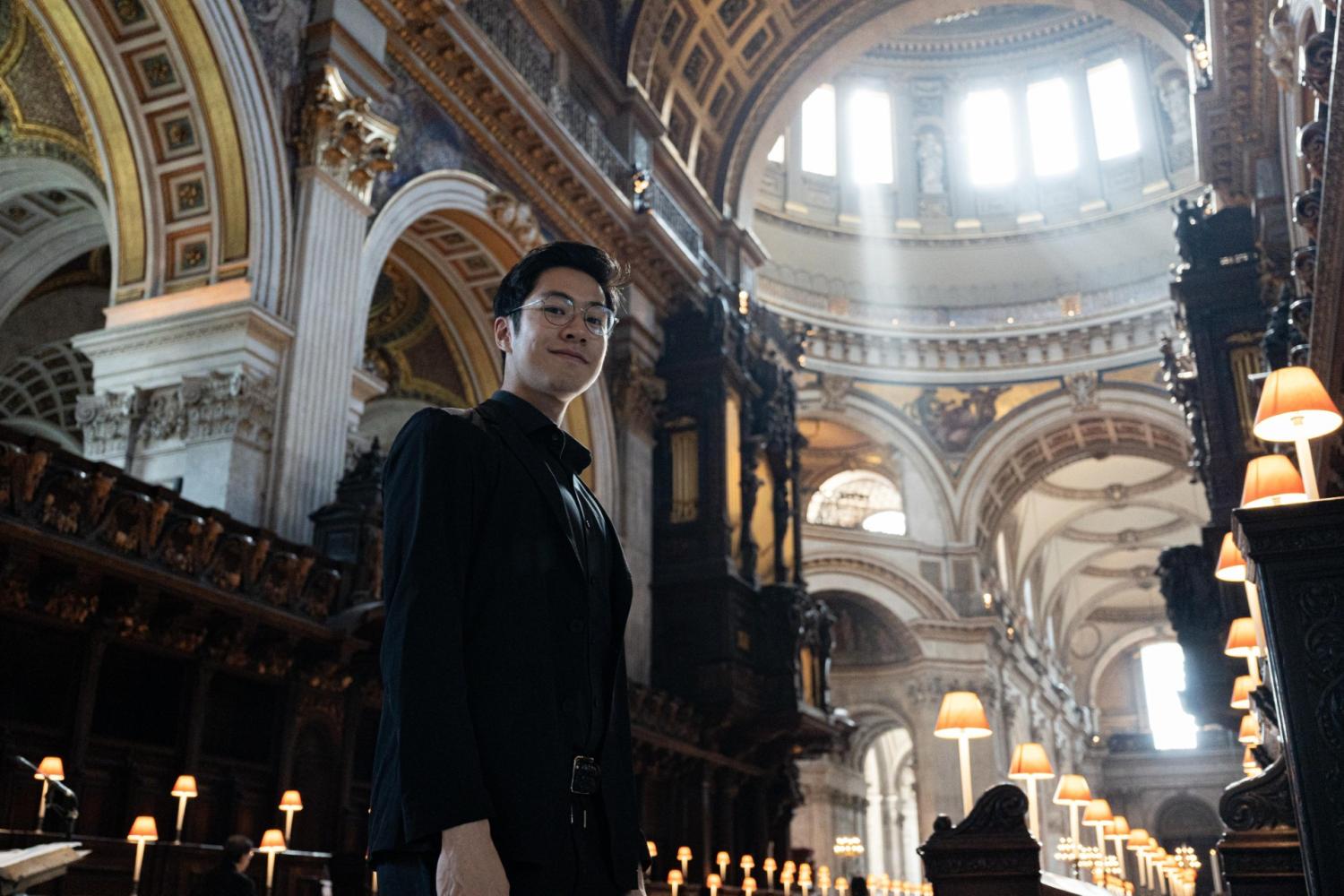 Jeremy Ng, Organ Scholar, stands in the Quire with the organ behind him.