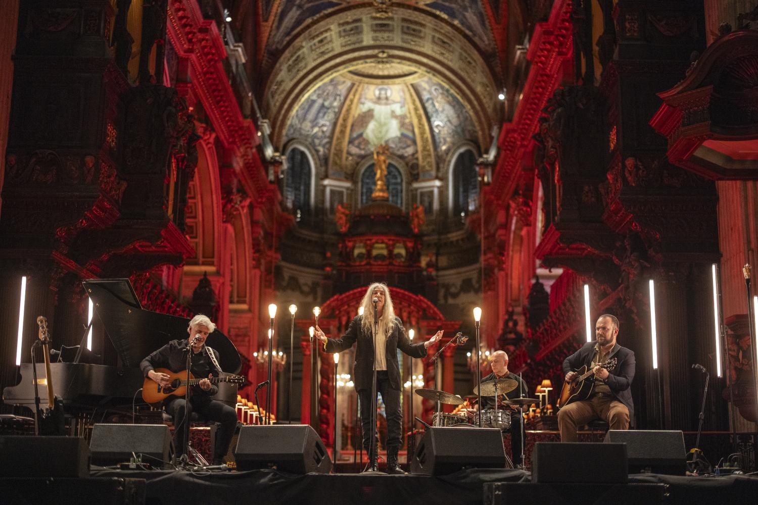 Patti Smith performs a concert under the Dome, surrounded by candles and red lighting.