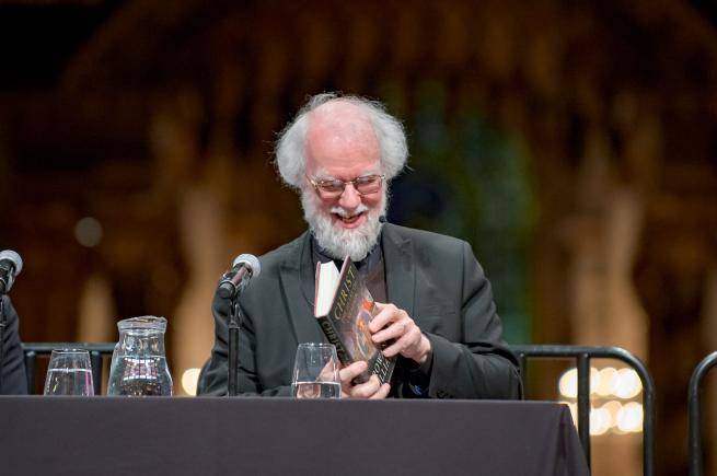 Rowan Williams smiling as he leafs through his book at an event at St Paul's Cathedral