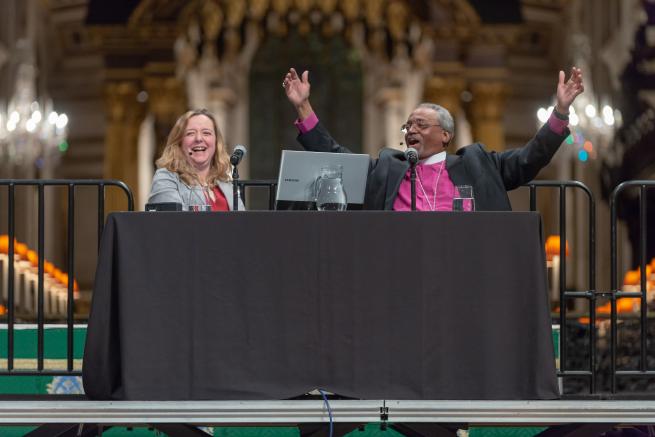 Bishop Michael Curry and Paula Gooder laughing onstage at an Adult Learning event in the cathedral