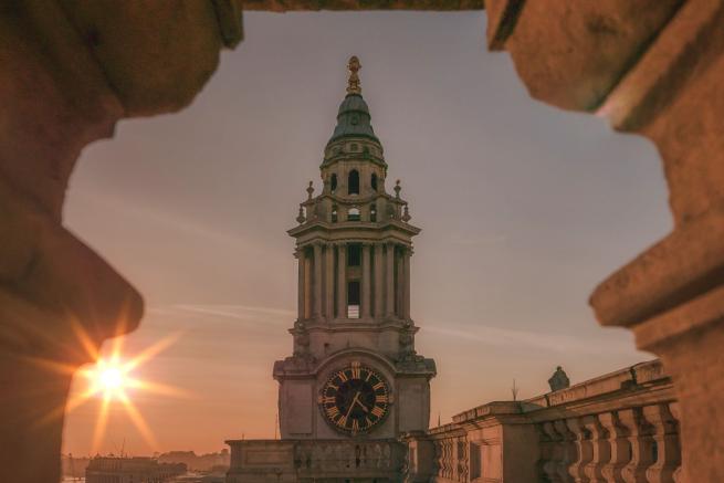 Focus on bell tower with sun in background 