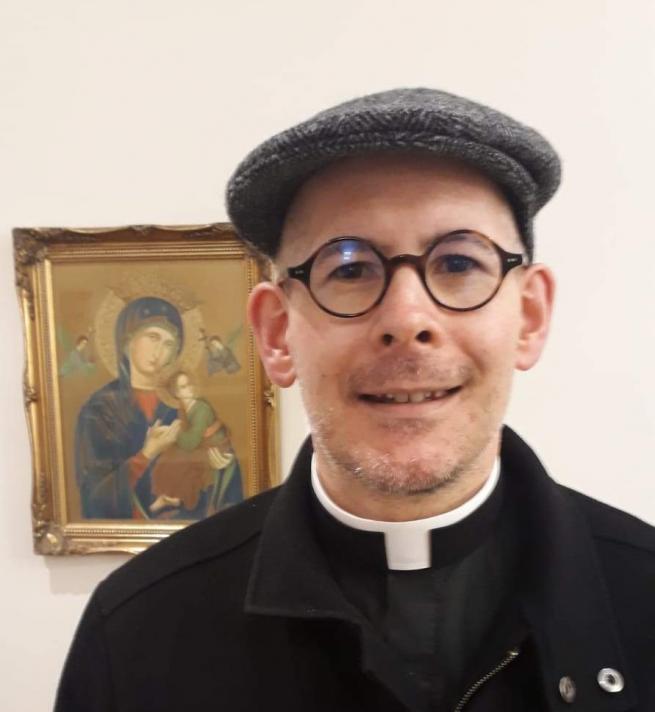 The Reverend Andrew Richardson in cap, glasses and clerical collar 