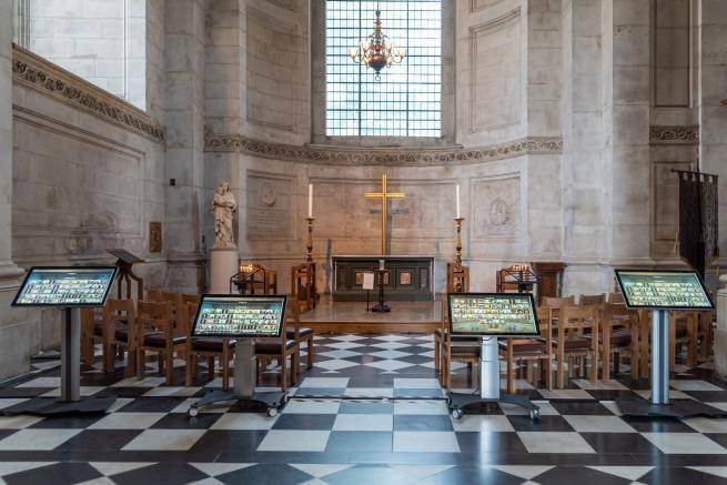 Four screens showing the Remember Me online memorial are placed in front of the Middlesex Chapel