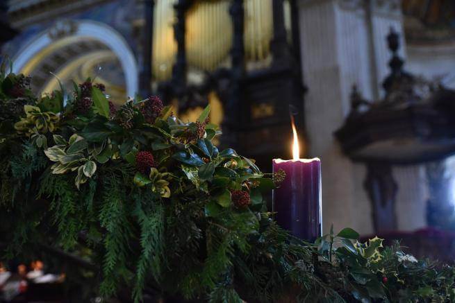 An image of a lit purple candle in the Advent wreath with the organ pipes in the background