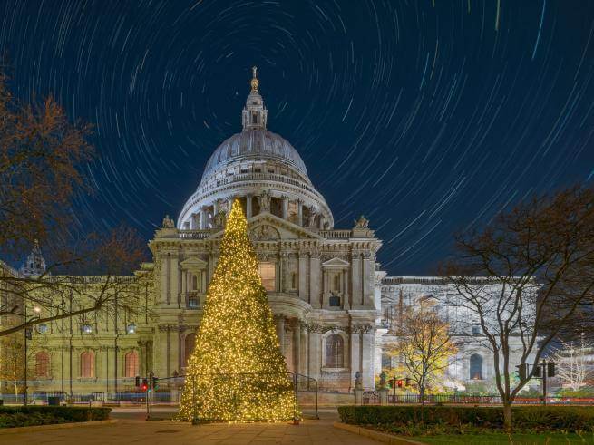 The exterior of St Paul's Cathedral at night with a Christmas tree in the foreground