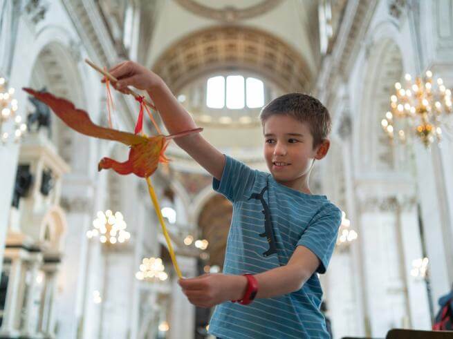 A young boy holds a paper model of a phoenix inside the Cathedral