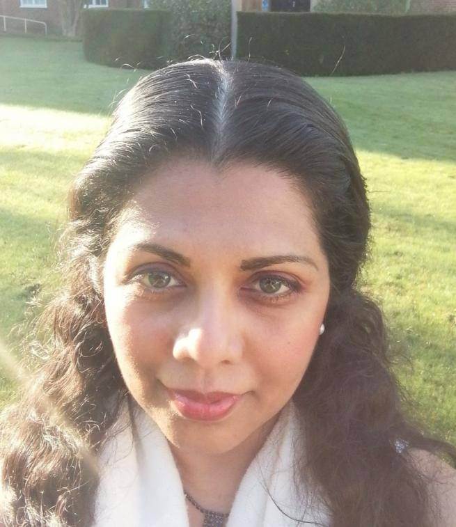 Sanjee Perera, an Asian woman with long brown hair, photographed on a sun-dappled lawn