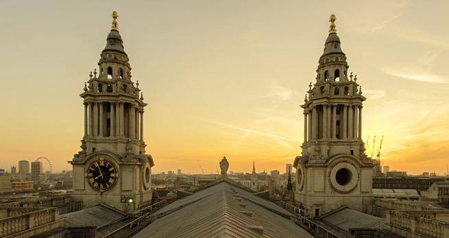 a view west from the roof looking towards the north west bell tower and south west clock tower as the sun sets behind the north west bell tower