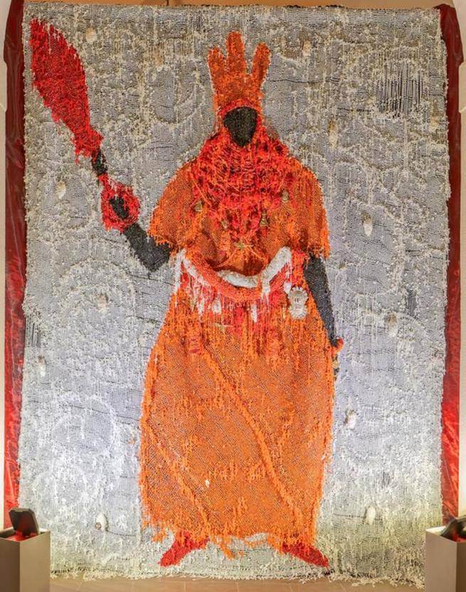 The artwork Still Standing is a mixed media installation, combining rosary beads and Benin bronze hip ornament masks to depict an Oba (King) of Benin. 