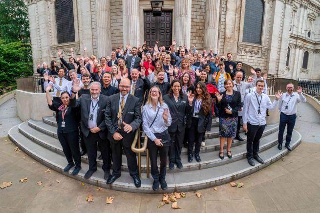 St Paul's Cathedral staff gathered in a group waving to the camera.