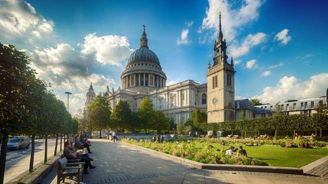 The cathedral from the south east with sunny blue skies and people sitting on the grass and benches in the foreground