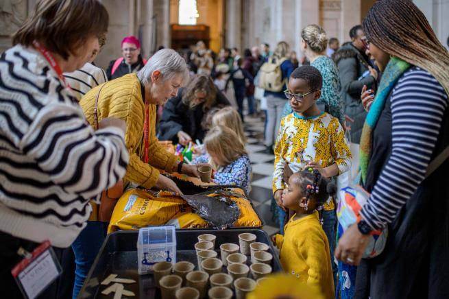 A group of young children and their families gathered around a table filled with craft activities.