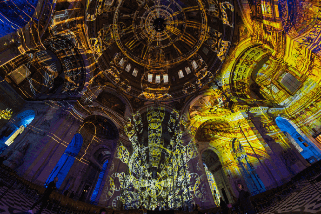A wide angled shot of the dome and nave, projected with clock designs in purple and gold.