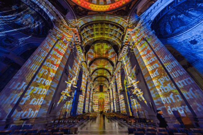 The nave of St Paul's with a projection of a manuscript over orange and blue lights.