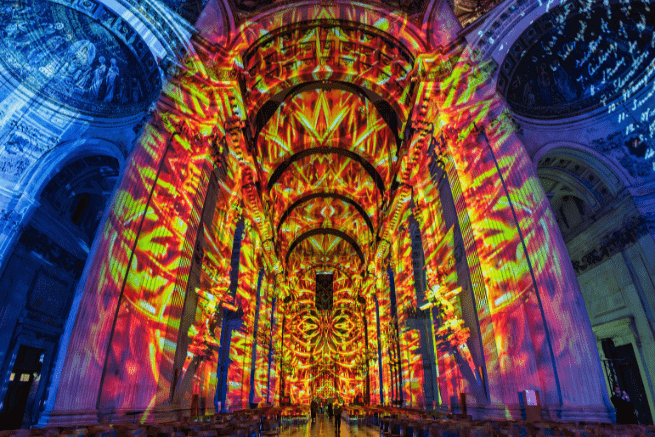 The nave of St Paul's, with a projection of red and orange flames depicting the Great Fire. On each side the walls are blue.