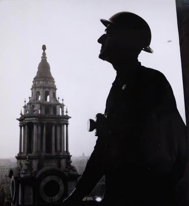 a silhouette of a male figure wearing a hat against a background of St Paul's bell tower
