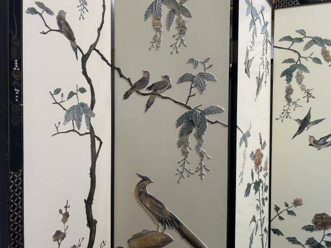 A cream lacquered silk folding screen with embroidered birds sitting on branches, flowers and peacocks