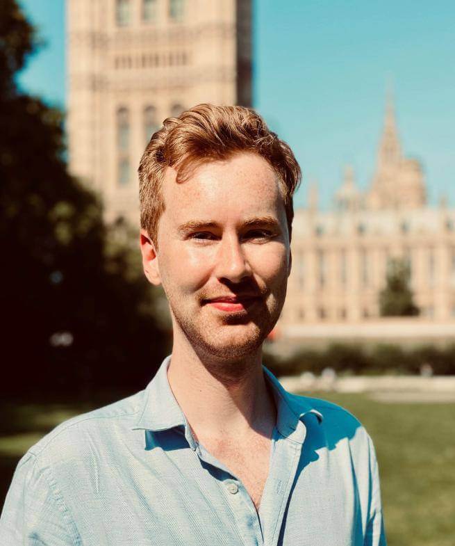 James Roberts, a white male wearing a blue shirt with collar standing in front of a cathedral