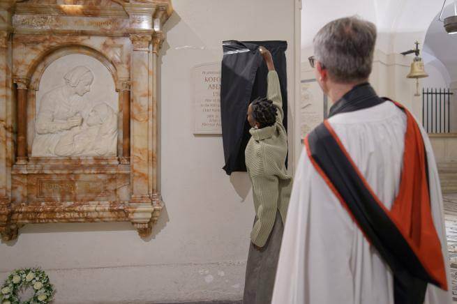 A woman unveils a memorial plaque in the Crypt.