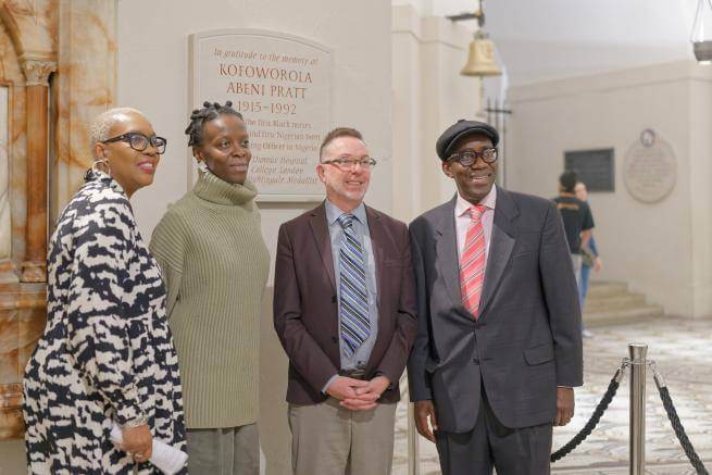 A group of people stand in front of a memorial plaque in the Crypt.