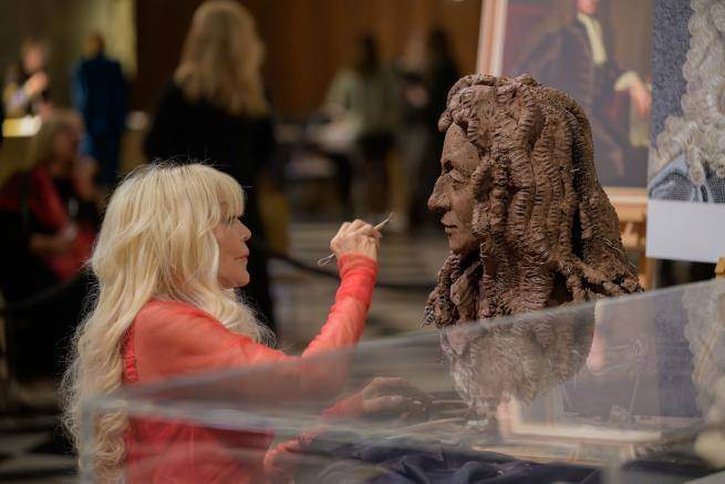 Lady Petchey sculpting a bust of Christopher Wren from dark clay.