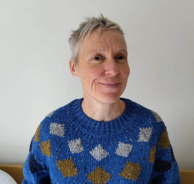 A woman with short grey hair wearing a blue sweater