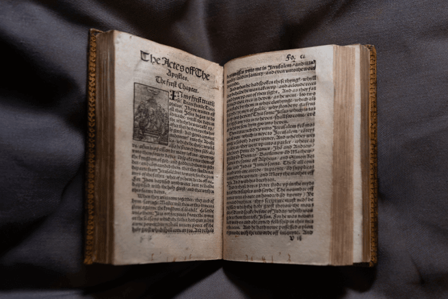 The 500 year old Tyndale bible open on a grey background