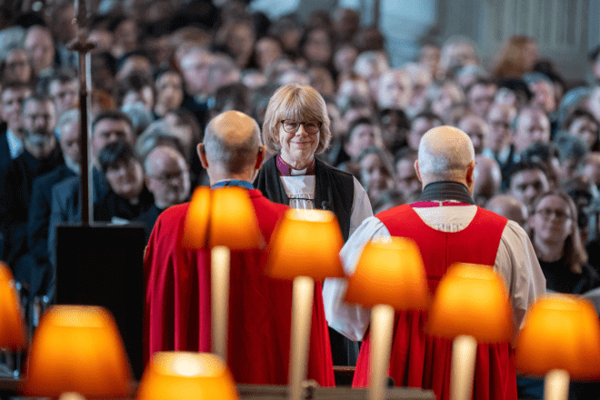 Archbishop Sarah stands in front of two bishops at the altar.