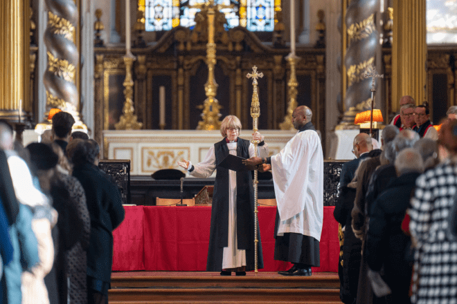 Archbishop Sarah holds a cross in front of the altar