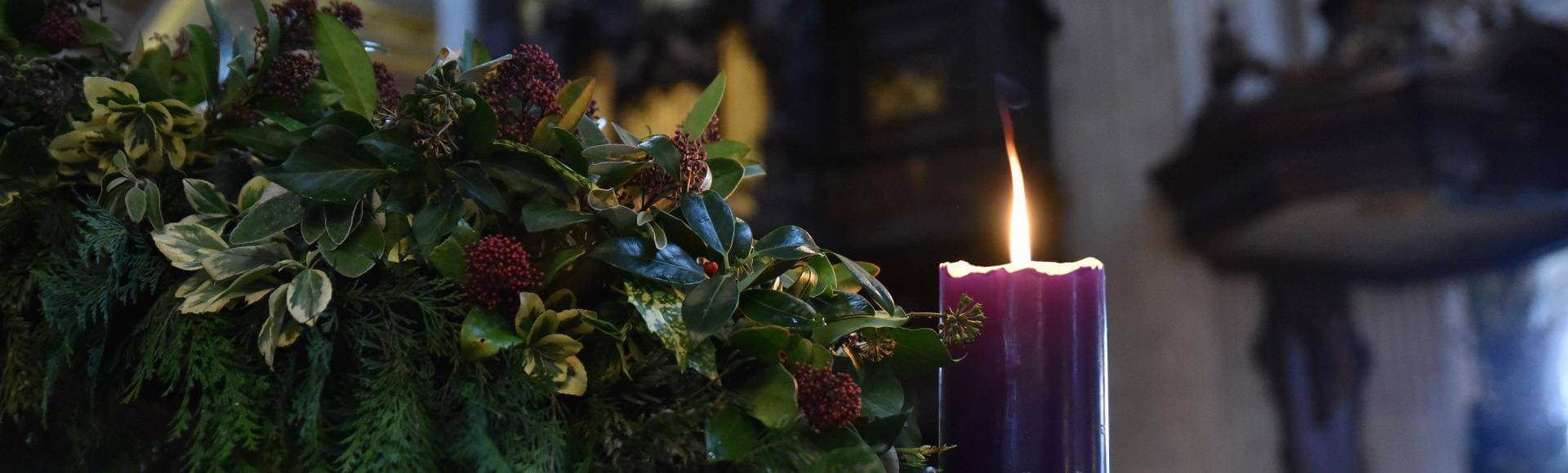 An image of a lit purple candle in the Advent wreath with the organ pipes in the background