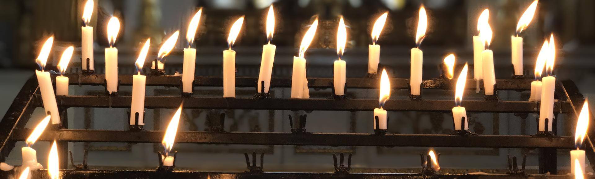 A series of lit candles on the candle stand in the cathedral