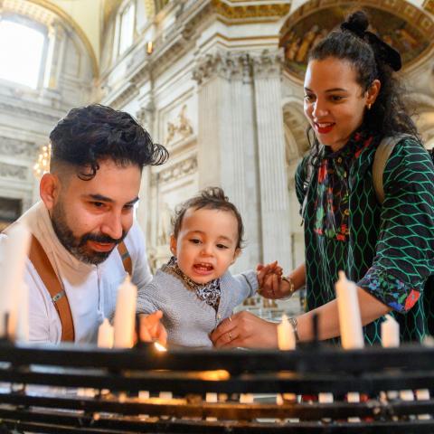 young family with baby lighting candles prayer