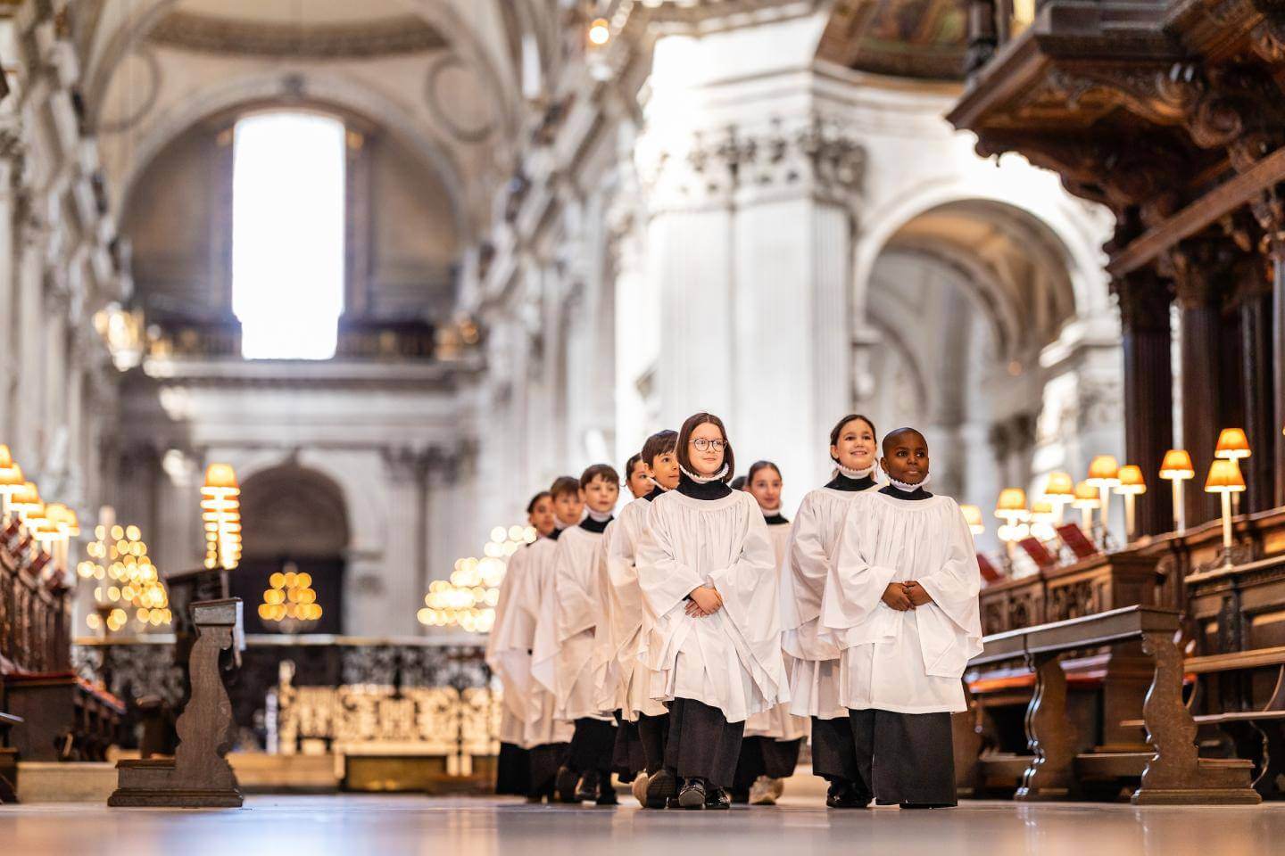 Girl and boy choristers in robes walking in the quire