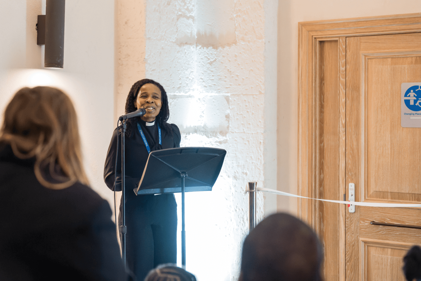 People listening to a female speaker at the Changing Places opening celebration