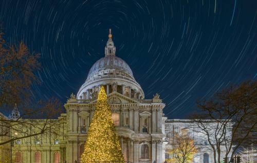 The exterior of St Paul's Cathedral at night with a Christmas tree in the foreground