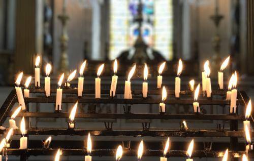 A series of lit candles on the candle stand in the cathedral
