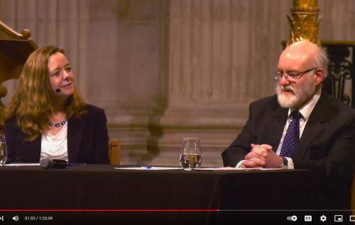 Paula Gooder and John Barton sit at a table in front of the dais at St Paul's Cathedral. John is talking and Paula smiling as she listens to him.