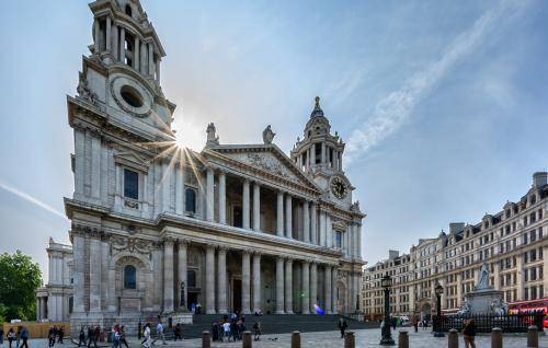 The west front of the cathedral with tourists milling round and sun shining over head