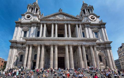 The west front of the cathedral with tourists milling round and sun shining over head