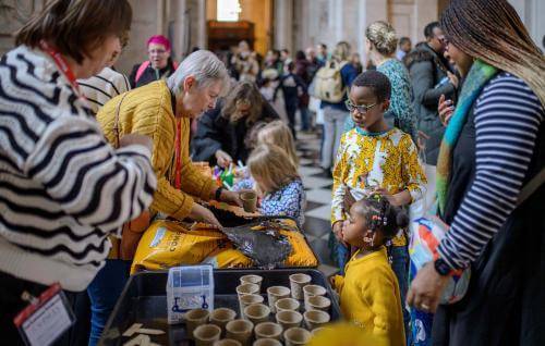A group of young children and their families gathered around a table filled with craft activities.