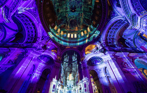 The dome and south transept lit with purple projections, featuring an image of the Old St Paul's Cathedral.