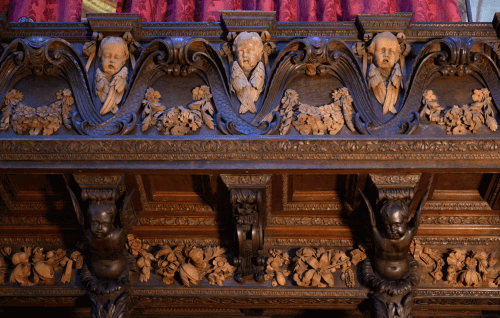 A close up shot of the Grinling Gibbons carvings in the Quire, featuring three cherubs surrounded by floral garlands.