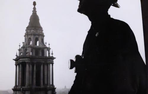 a silhouette of a male figure wearing a hat against a background of St Paul's bell tower