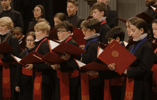 Choir in black and red robes singing holding red and black books