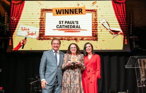Kim Newland holds award with presenters in front of a screen that says 'Winner: St Paul's Cathedral: Best Cultural Experience'