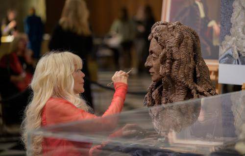 Lady Petchey sculpting a bust of Christopher Wren from dark clay.