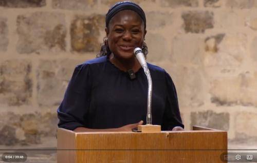 Bisi stands at the microphone and lectern as she delivers a talk in the Wren Suite in St Paul's Cathedral