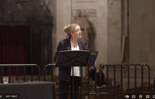 Paula stands at a lectern speaking from a stage in St Paul's Cathedral