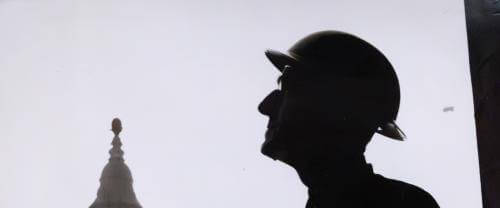 a silhouette of a male figure wearing a hat against a background of St Paul's bell tower