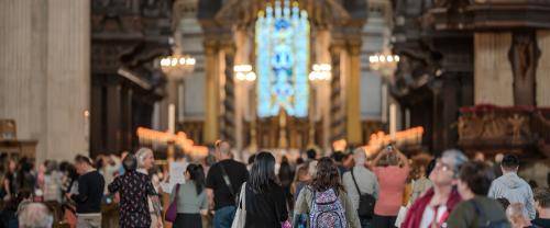 People wander through the Nave with evening light at the east window